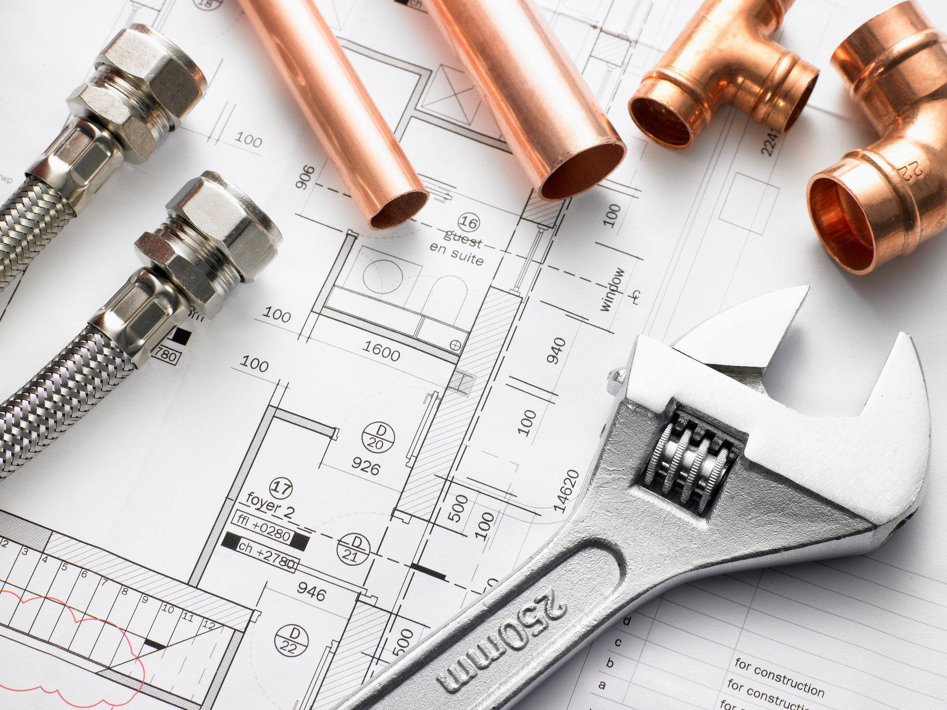 Residential plumbing tools, copper pipe and fittings on a home blueprint